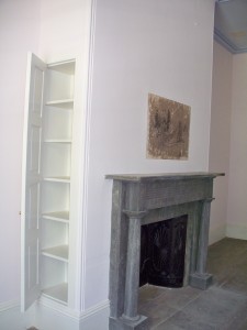 A marble mantle surrounds this fireplace featuring a cast iron fireback.